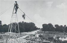Waesta cableway for measuring the water velocity at different flood heights; gauging the Omuramba Omatako on Farm Ousema, February, 1962. In the chair is Mr. H. W. Stengel. On the tower Mr. W. F. W. Holch who constructed the apparatus. Photograph Dr. O. Wipplinger.
